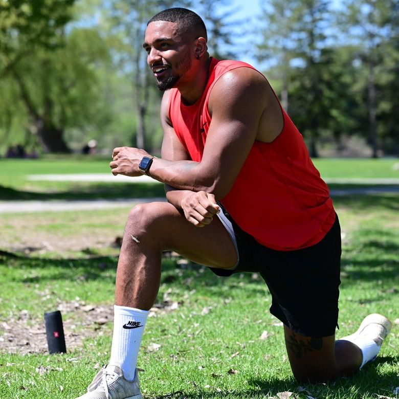 Jackeil Lavergne kneeling on the grass in a park, smiling
